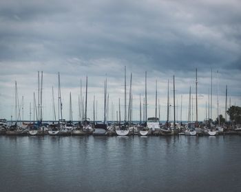 Boats in calm sea against cloudy sky