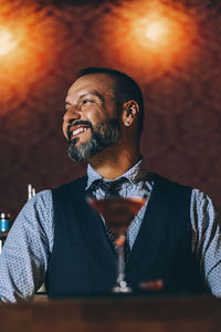 Smiling man looking away while sitting in bar