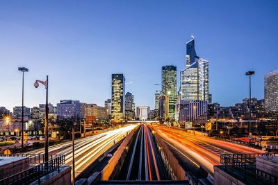 Light trails on highway leading towards city buildings