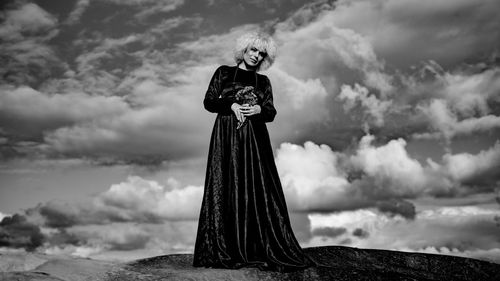 Low angle view portrait of woman standing against cloudy sky