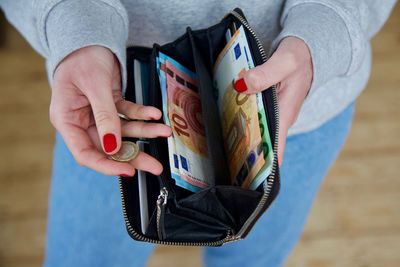 Midsection of woman holding coin and purse with paper currency