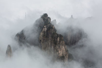 Rocky mountains amidst clouds against sky