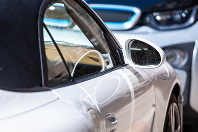 Row of cars parked on the side of the street, white sports car in the foreground, closeup of details