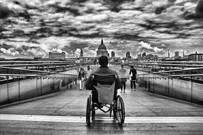 Rear view of people sitting on bridge