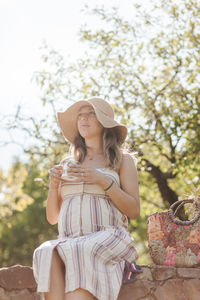 Low section of woman wearing hat against trees