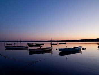 Boats moored in sea against clear sky during sunset