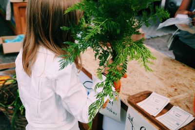 Rear view of girl selling fresh carrots at farmer market