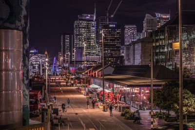 Illuminated street amidst buildings in city at night