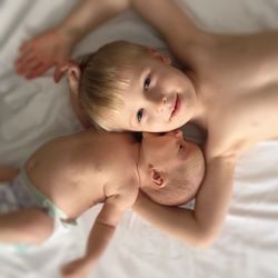Directly above shot of siblings lying on bed