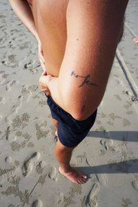 Low section of man on sand at beach