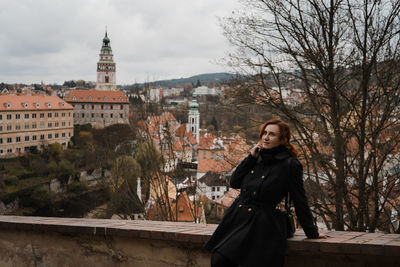 Woman standing by building against trees