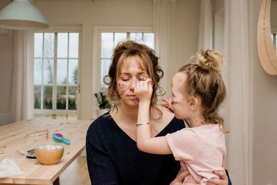 Mother and daughter playing dress up with make up & glitter together