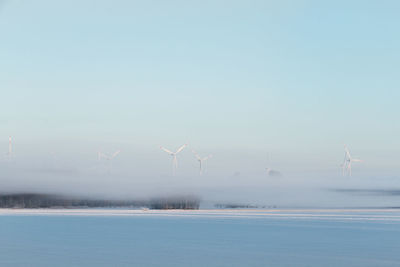 Wind turbines in water against sky