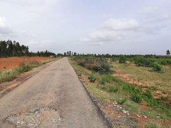 Dirt road along landscape against sky