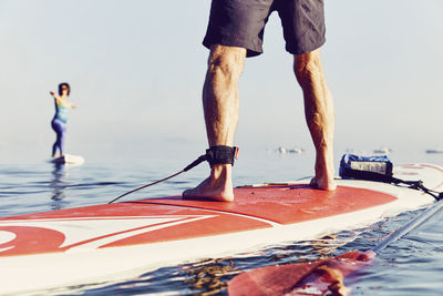 A group of standup paddle boarders doing yoga at sunrise in the fog