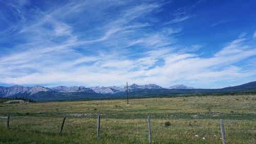 Scenic view of field and mountains against blue sky