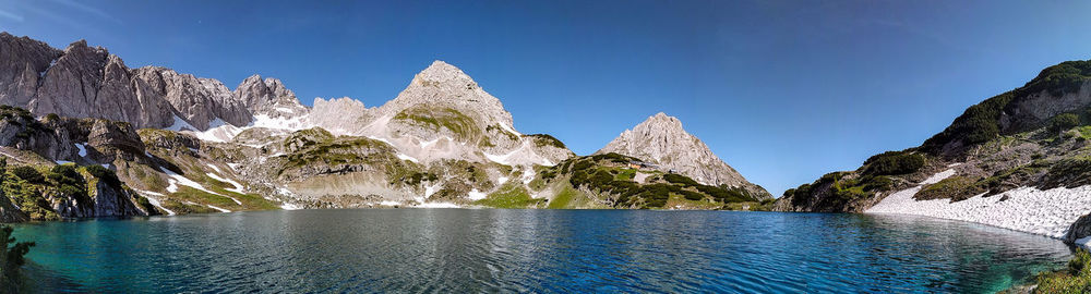 Scenic view of sea and mountains against clear blue sky