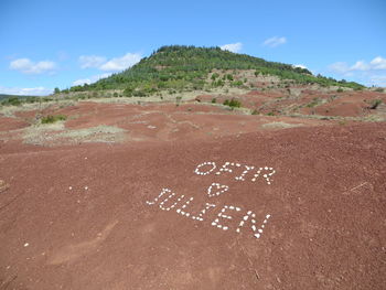Text written on land against sky