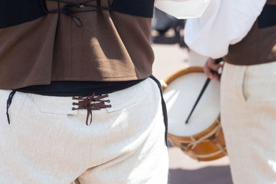 Midsection of musicians playing drum during traditional festival