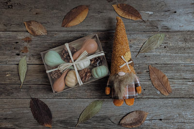 A gnome toy and a box with pumpkins and pine cones on the table.