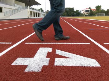 Low section of man walking on running track