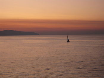 Sailboat sailing on sea against sky during sunset