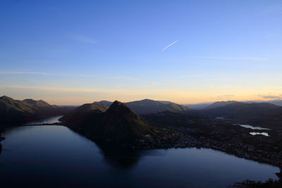 Scenic view of lake by mountains against sky during sunset