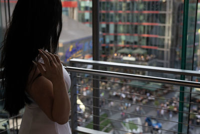 Side view of woman standing by railing and window