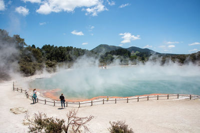 Panoramic view of people on shore against trees