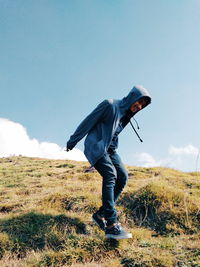 Side view of man standing on field against sky