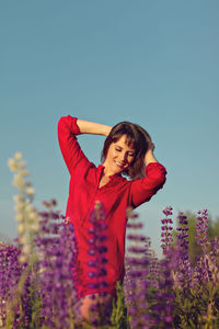 Beautiful woman standing on field against sky