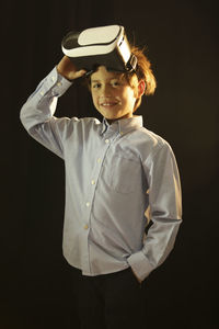 Portrait of happy boy standing against black background