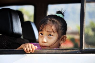 Portrait of cute girl looking through window