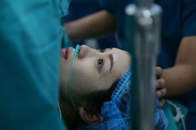 Close-up of female patient crying while lying on bed in hospital