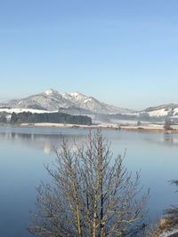 Scenic view of lake and snowcapped mountains against clear blue sky