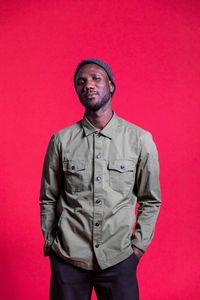 Portrait of young man standing against red background