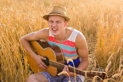 Young man playing guitar on field