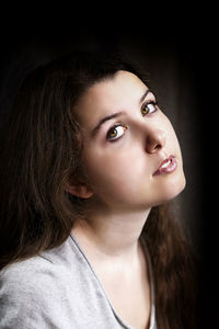 Close-up portrait of beautiful young woman against black background