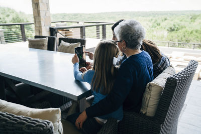 Granddaughters using tablet computer with grandmother on porch