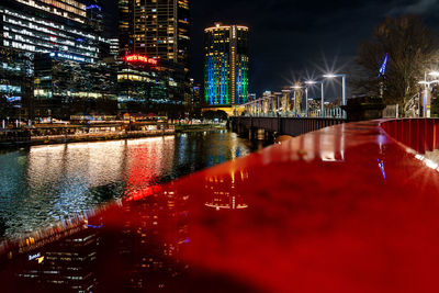 Illuminated bridge over river in city at night