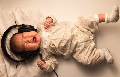 Crying baby girl listening music on bed