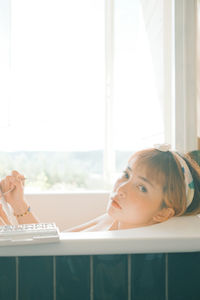 Portrait of woman painting while sitting in bathtub