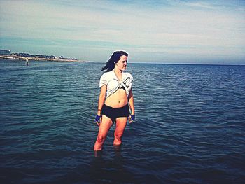 Young woman standing in sea against sky