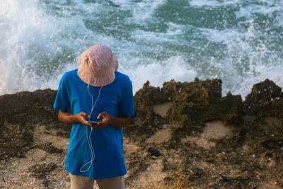 Rear view of young man standing at waterfall