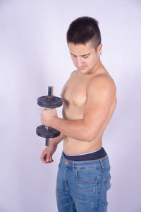 Full length of shirtless man standing against white background