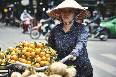 Midsection of woman with fruits on street in city