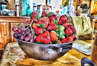 Fresh strawberries and grapes in metallic container on table