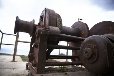 Close-up of old rusty wheel on field against sky