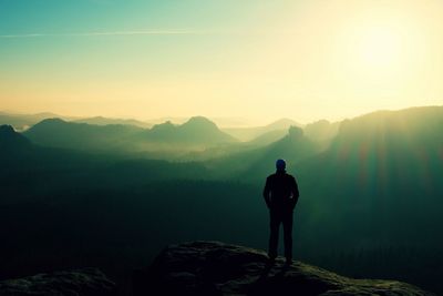 Rear view of man standing on mountain against sky