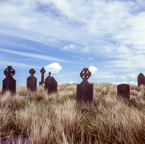 Metallic tombstone on field against sky